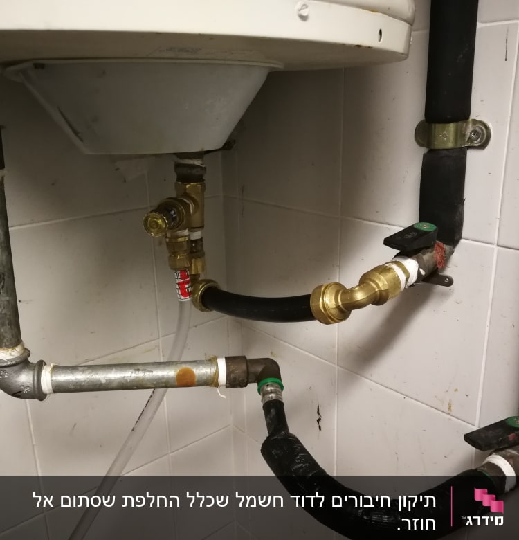 צינורות מתכת וברזים מתחת לדוד מים